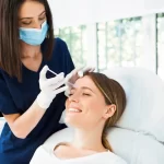 Smiling woman receiving Botox on her forehead. How long does Botox last for wrinkle reduction?