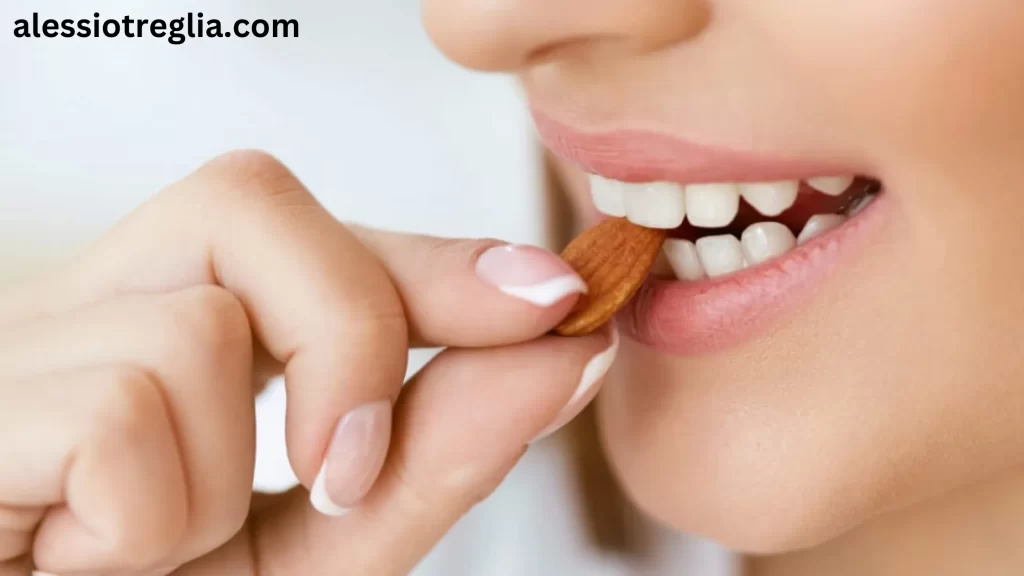 Woman eating an almond. Can you eat after a filling? Avoid hard foods like nuts immediately after a dental filling to prevent damaging the filling and ensure proper healing.